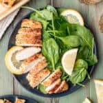 Panko chicken sliced on a plate with a spinach salad.