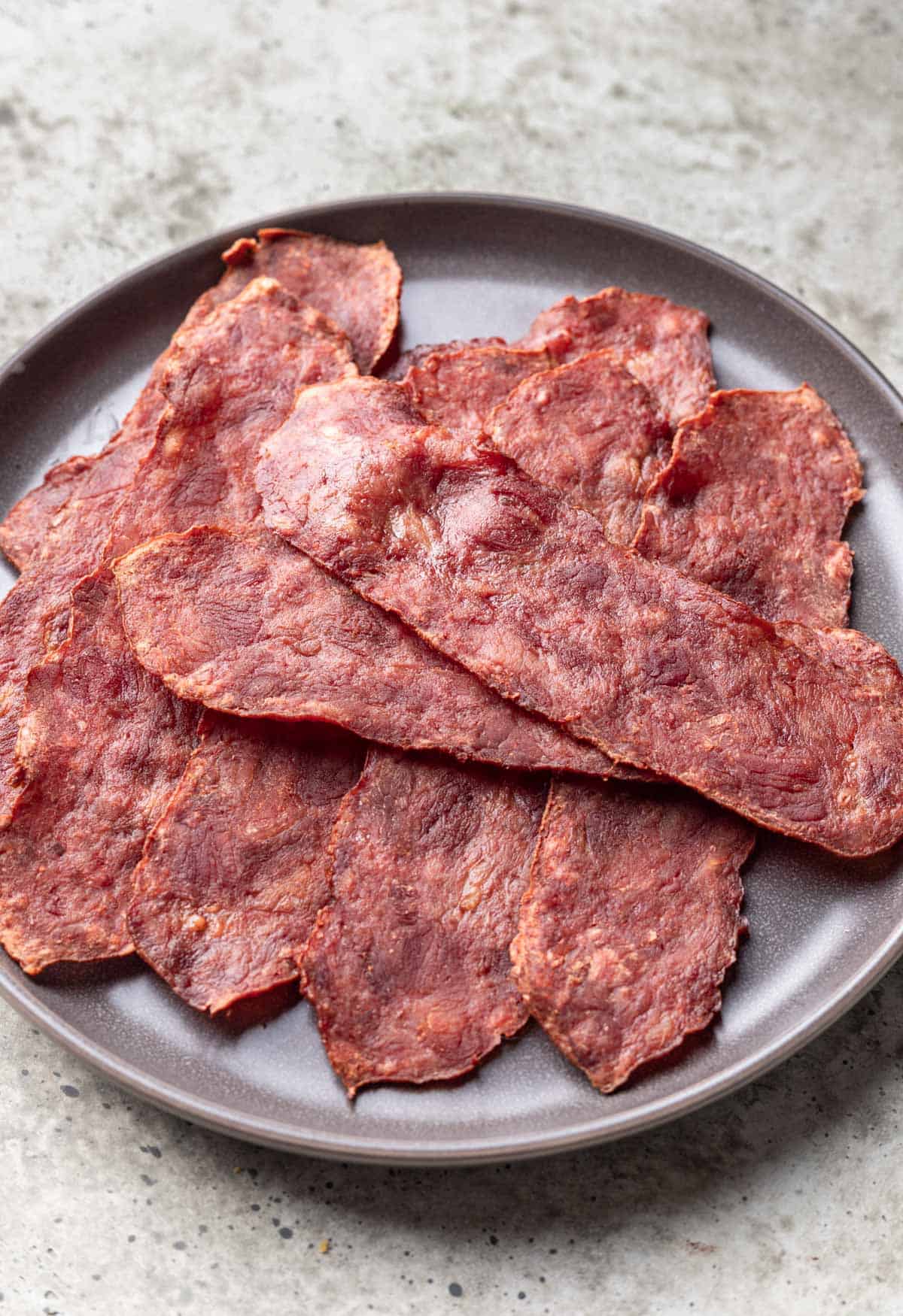 Crispy turkey bacon piled on a gray plate.