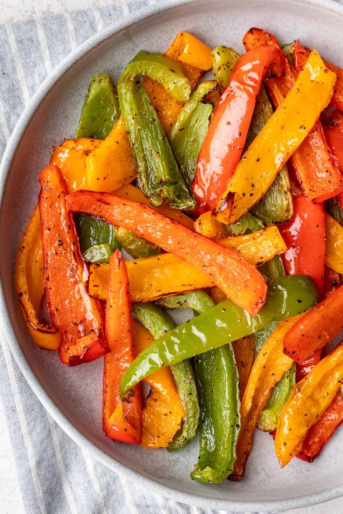 Air fryer bell peppers in a bowl with a blue towel next to it.