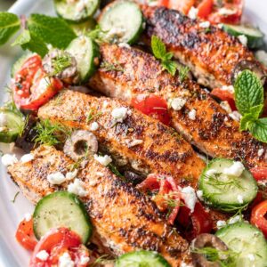 Greek salmon with cucumbers, tomatoes, and feta on a plate.