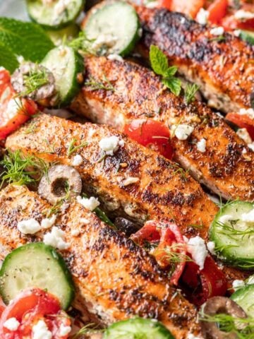 Greek salmon with cucumbers, tomatoes, and feta on a plate.