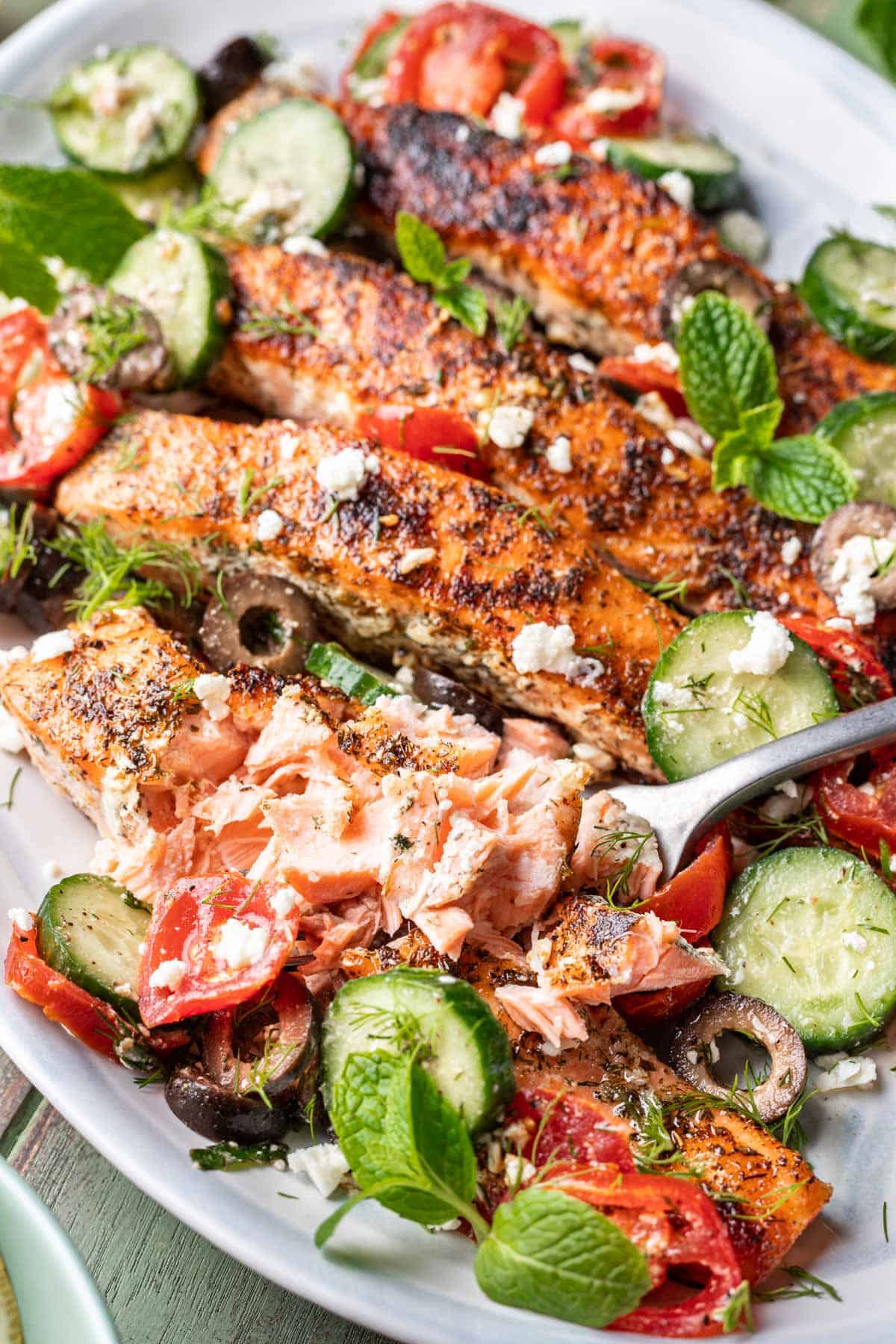 A fork showing the flakiness of the cooked salmon.