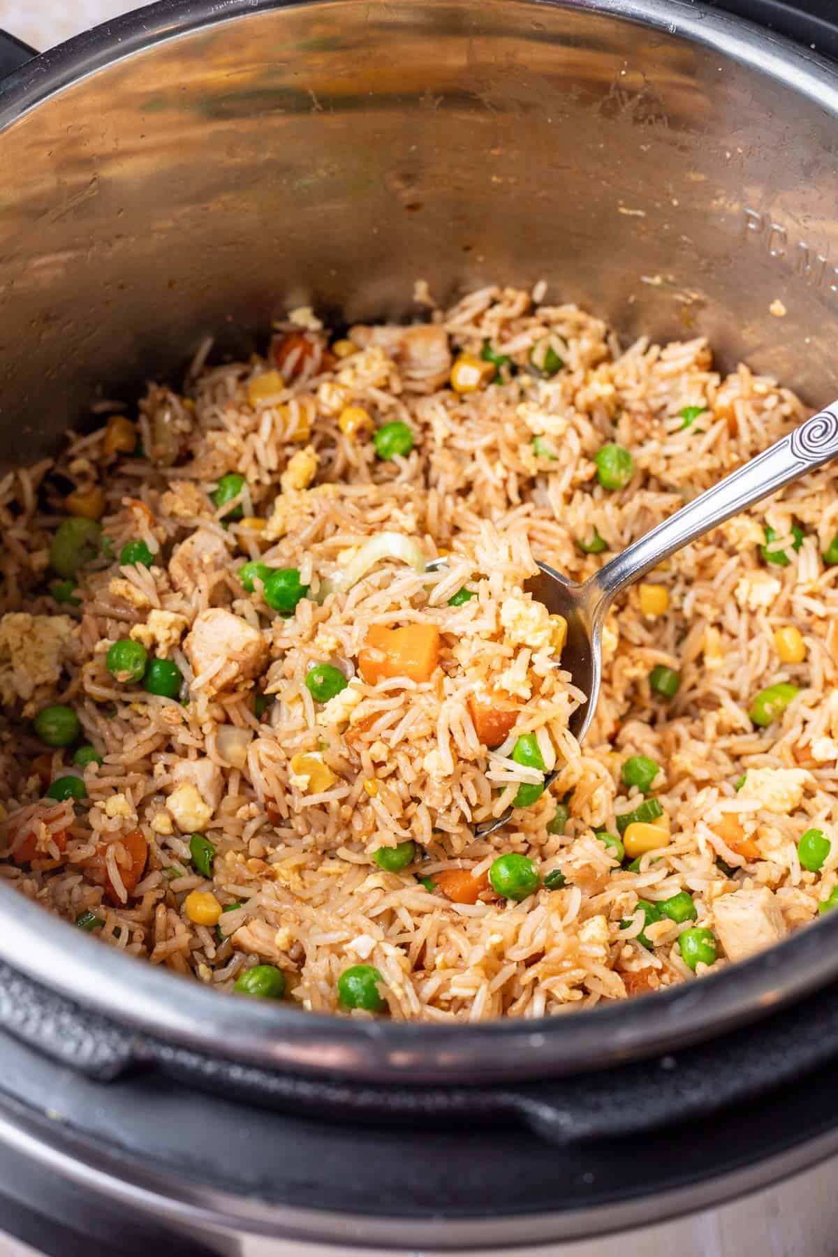 A spoon scooping chicken fried rice out of the instant pot.