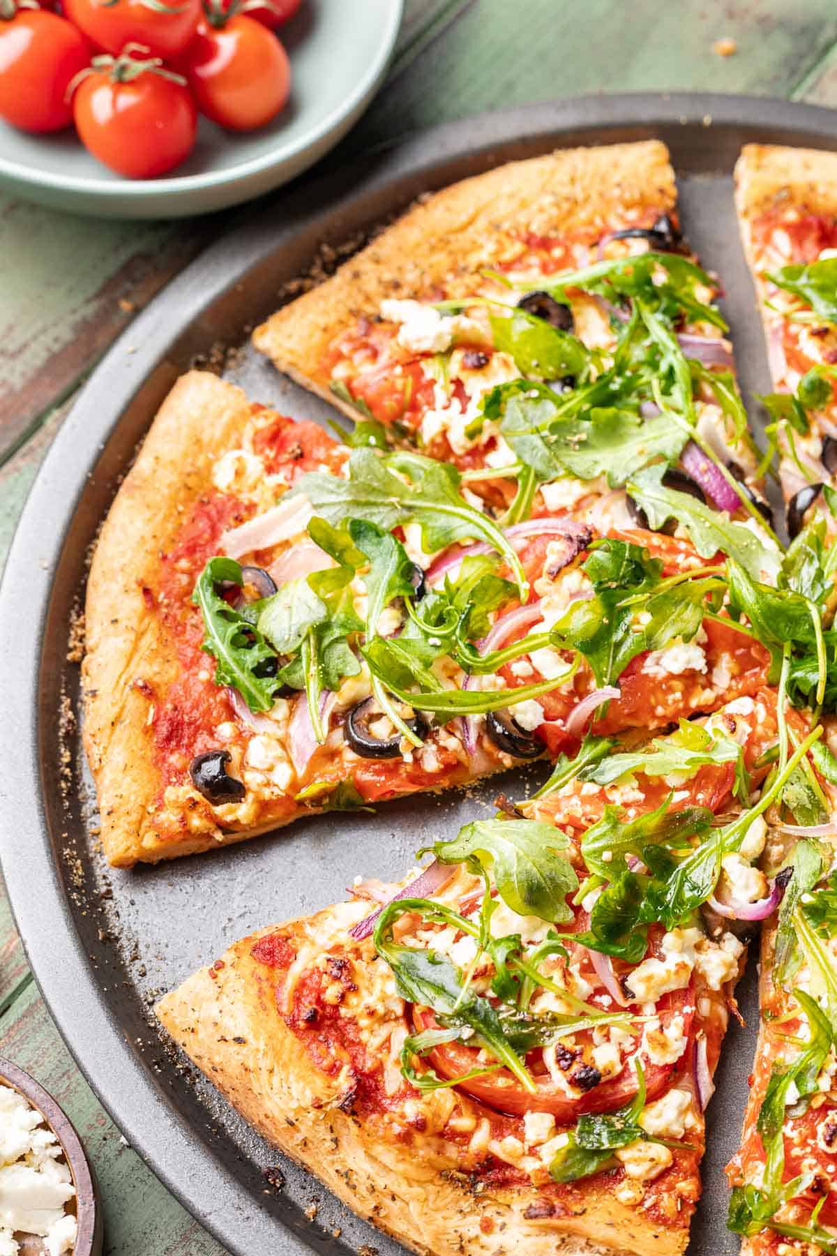 A slice of mediterranean pizza on a pizza pan.