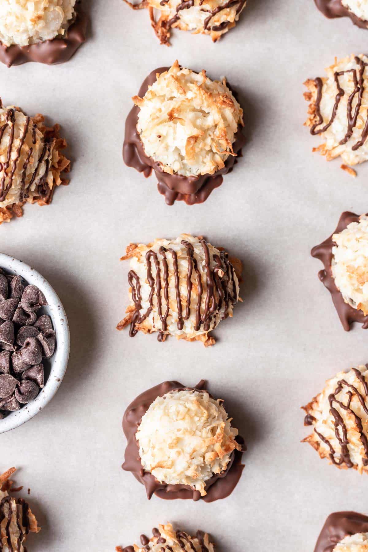 Coconut macaroons dipped in chocolate on a baking sheet.