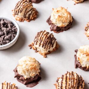 Coconut macaroons without condensed milk on a baking sheet, drizzled with chocolate on top.