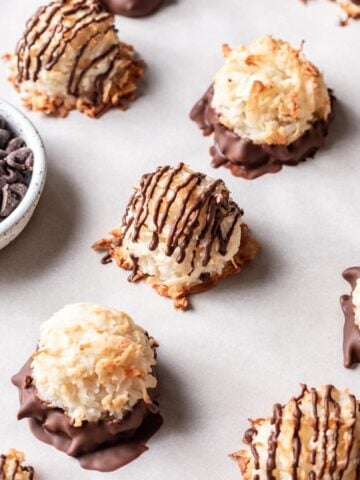 Coconut macaroons without condensed milk on a baking sheet, drizzled with chocolate on top.