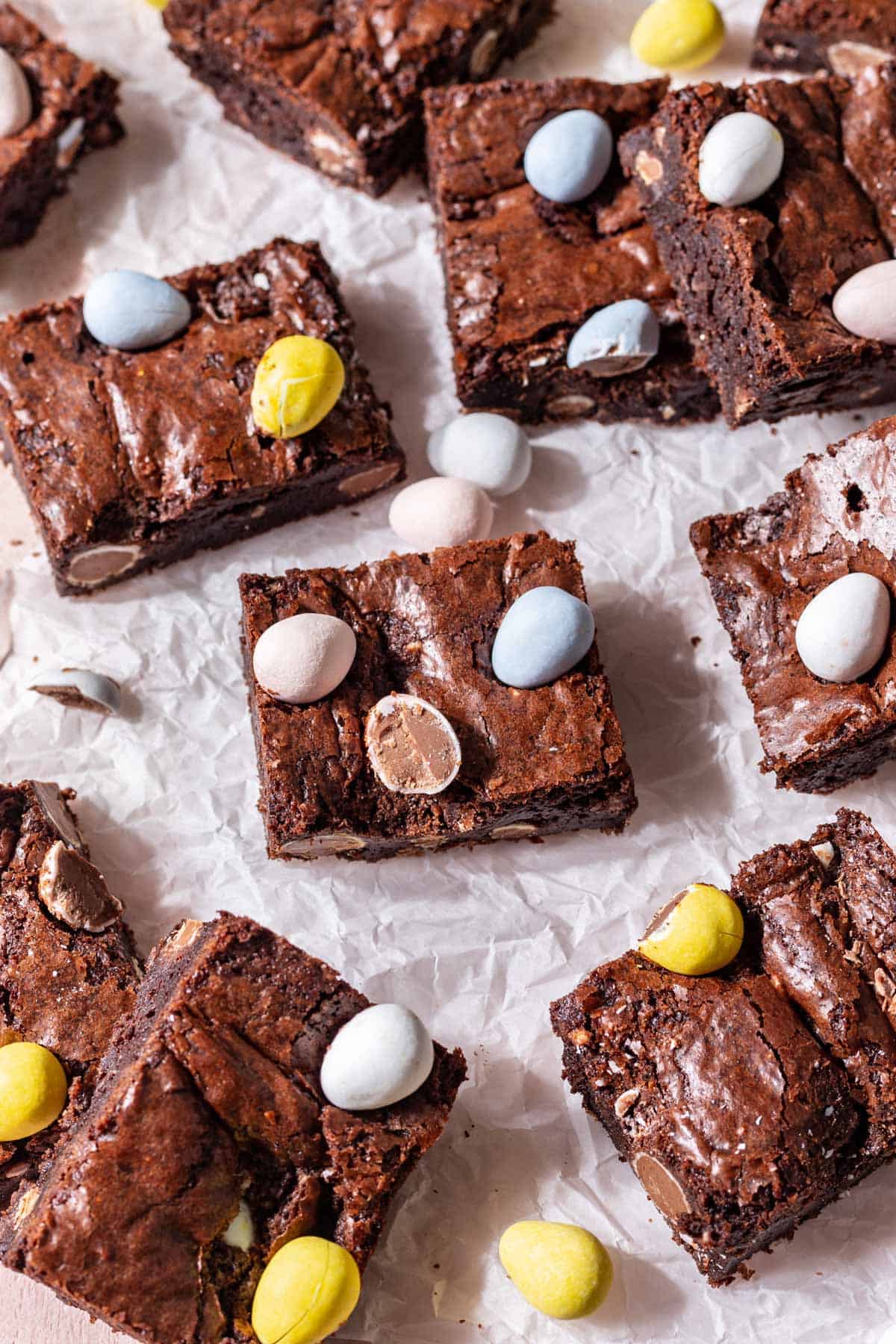 Rich, chocolatey brownies on parchment paper with mini easter eggs.
