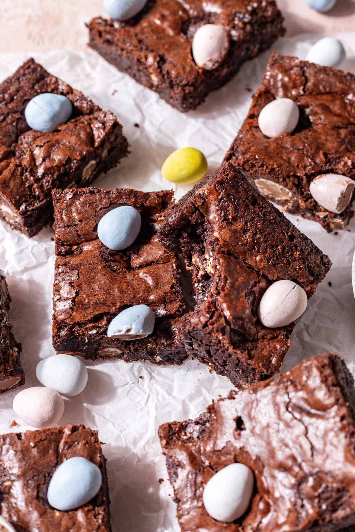 Mini easter egg brownies with a bite taken out on top of parchment paper.