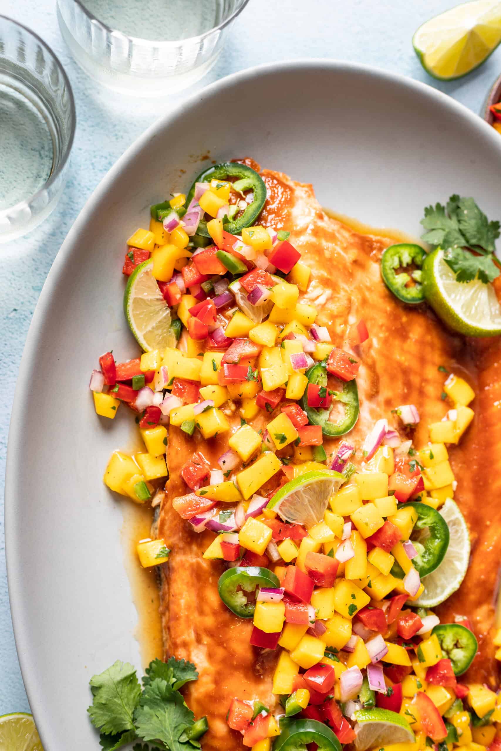 Serving platter with salmon, mango salsa, lime wedges, and cilantro.