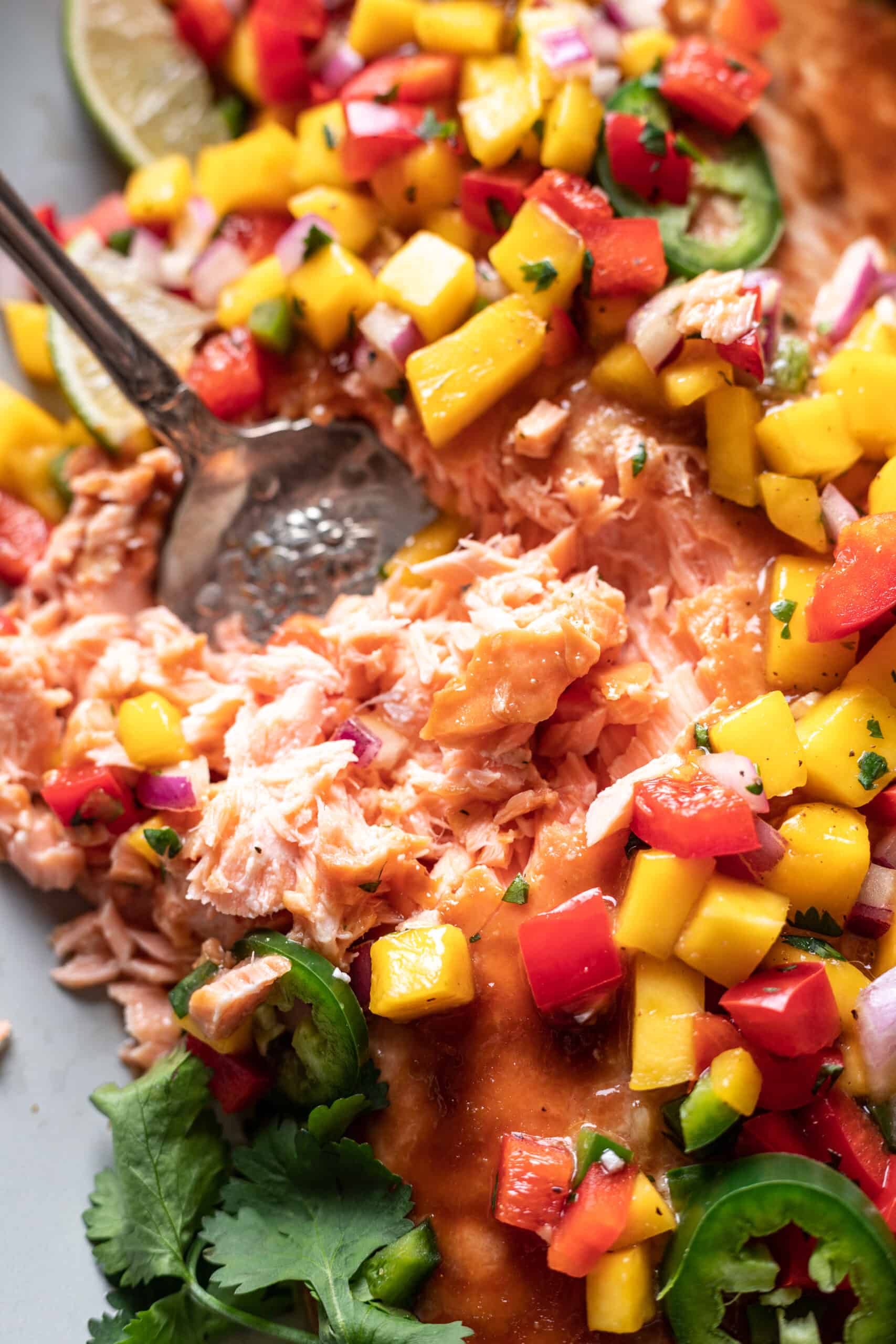 Flaky salmon on a serving platter with mango salsa on top.
