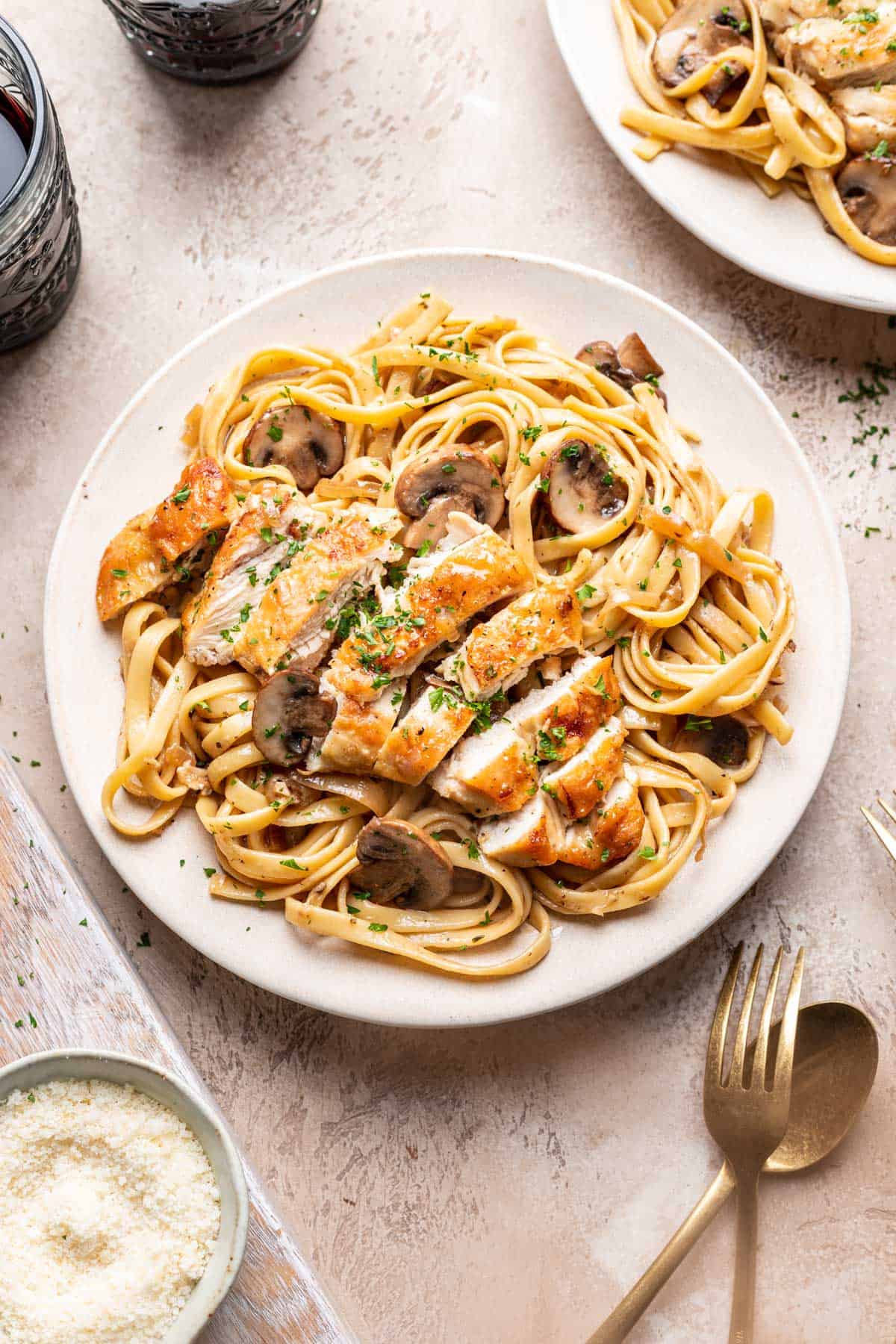 Sliced chicken marsala on fettuccine pasta garnished with parsley.