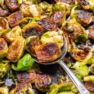 A serving spoon scooping maple balsamic brussels sprouts.