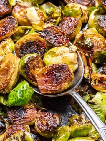 A serving spoon scooping maple balsamic brussels sprouts.