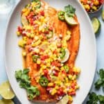 Baked salmon on a platter topped with mango salsa.