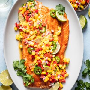 Baked salmon on a platter topped with mango salsa.