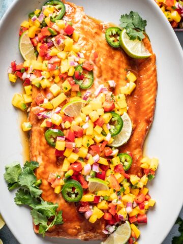 Baked salmon on a platter topped with mango salsa.