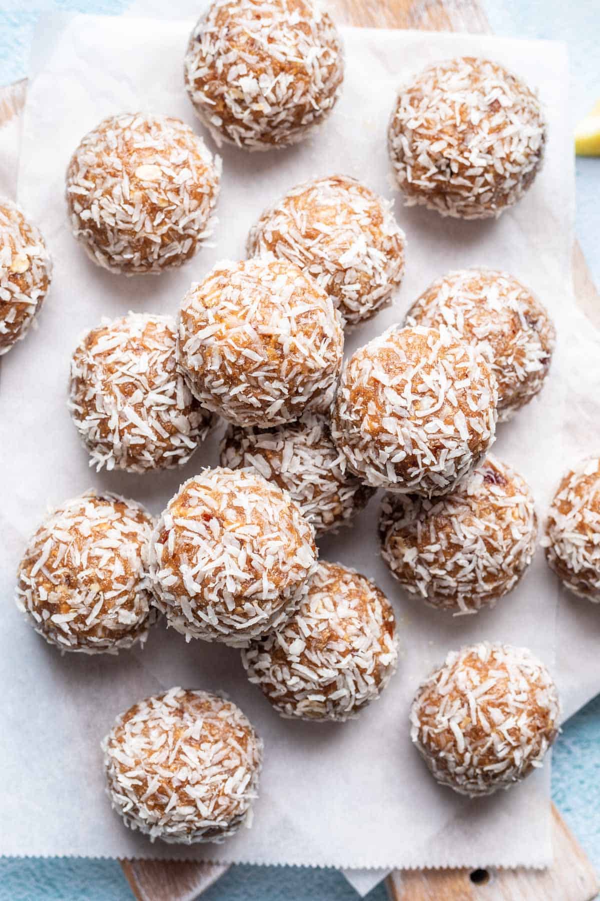 Lemon bliss balls rolled in desiccated coconut and stacked on a serving board.