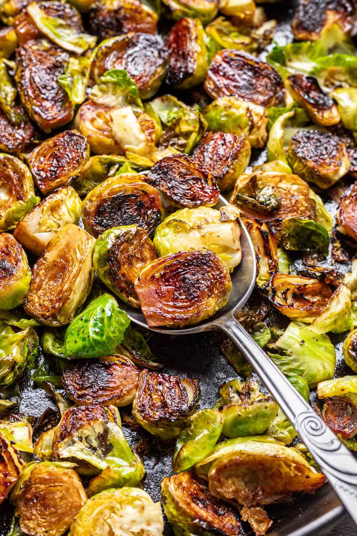 A serving spoon scooping maple balsamic brussels sprouts.