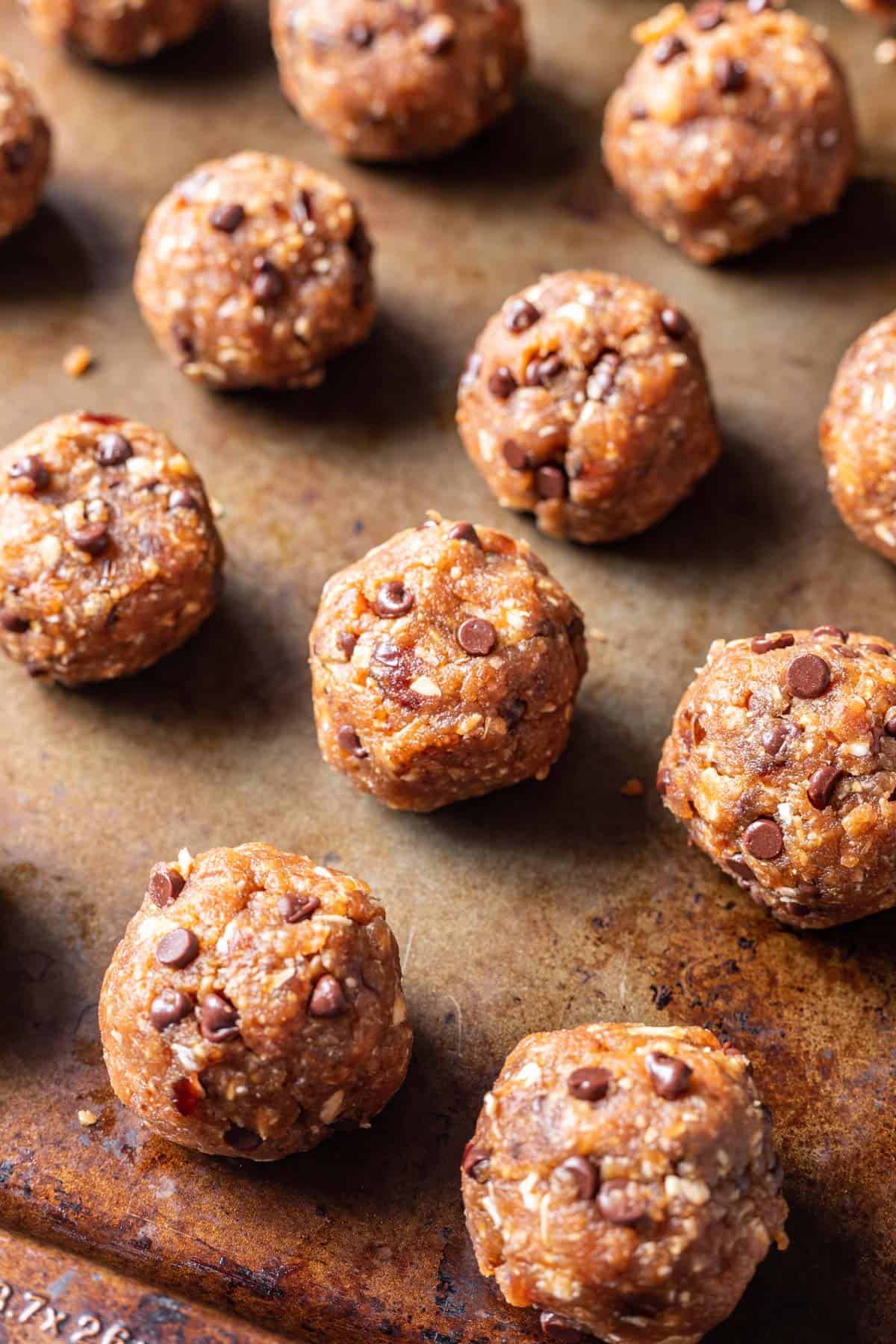 Peanut butter bliss balls rolled into balls on a baking sheet.