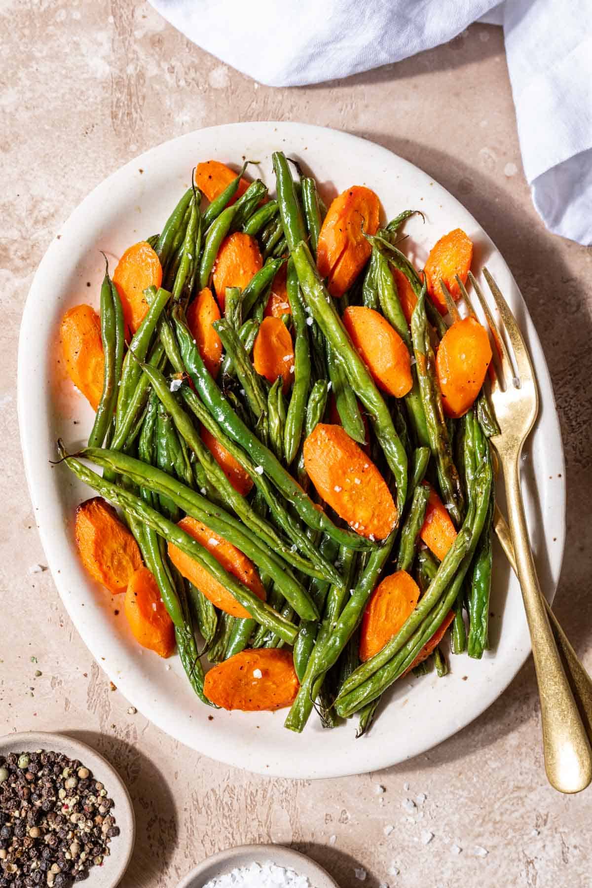 Roasted green beans and carrots on a serving platter.