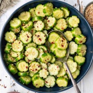 Spicy cucumber salad in a blue serving bowl.