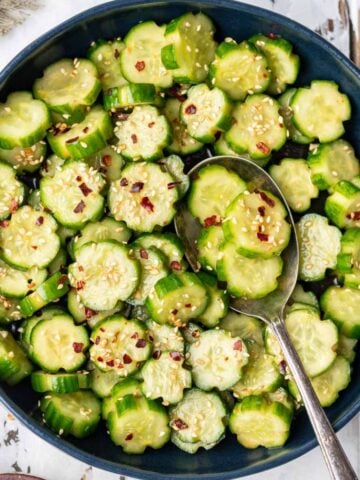 Spicy cucumber salad in a blue serving bowl.