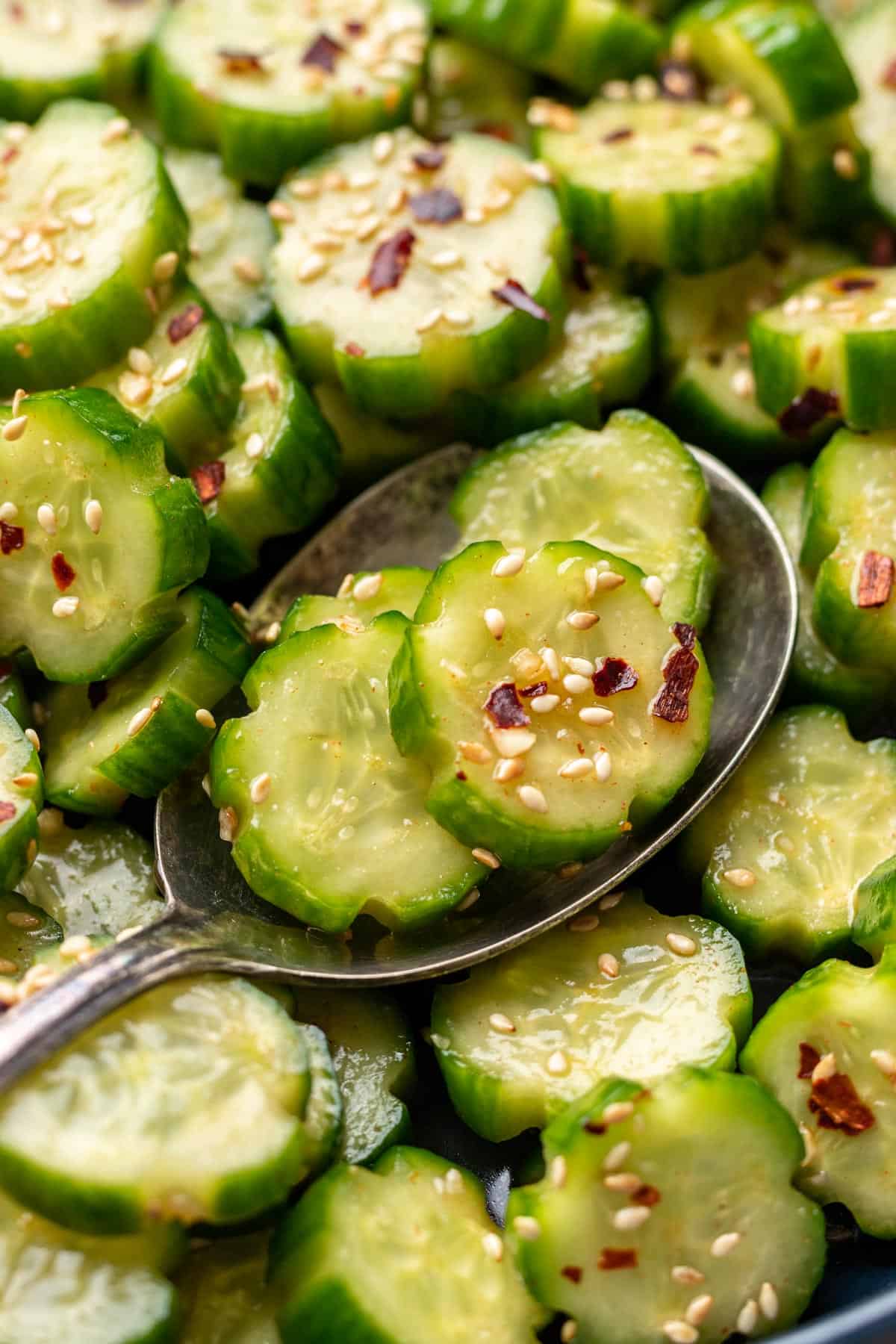 Spicy cucumber salad scooped with a serving spoon.