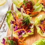 Spicy meatballs on a lettuce cup with shredded carrots and purple cabbage.