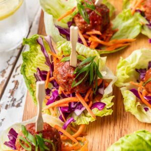 Spicy meatballs on a lettuce cup with shredded carrots and purple cabbage.