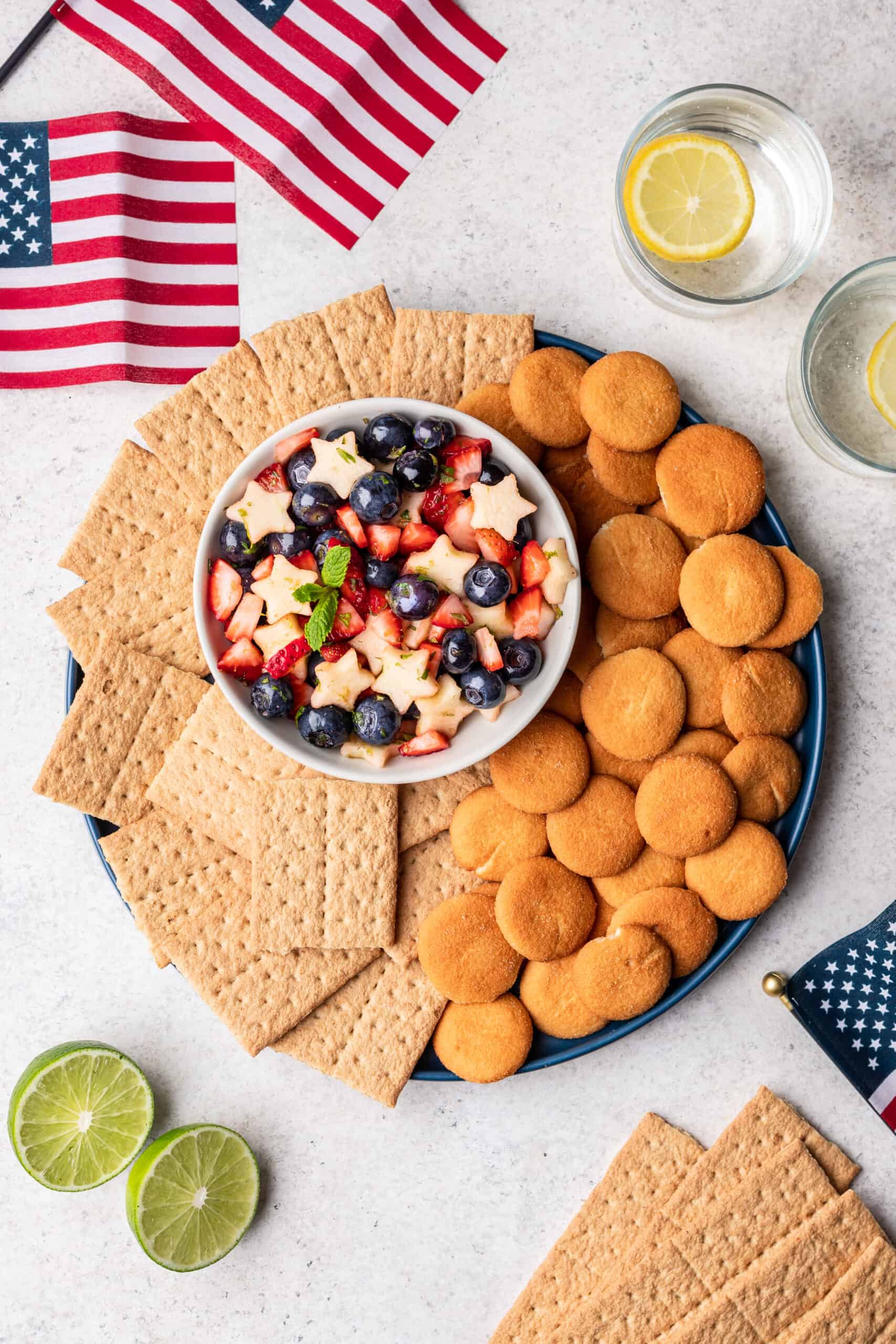 Red, white, and blue fruit salsa on a serving platter with nilla wafers and graham crackers for dipping.