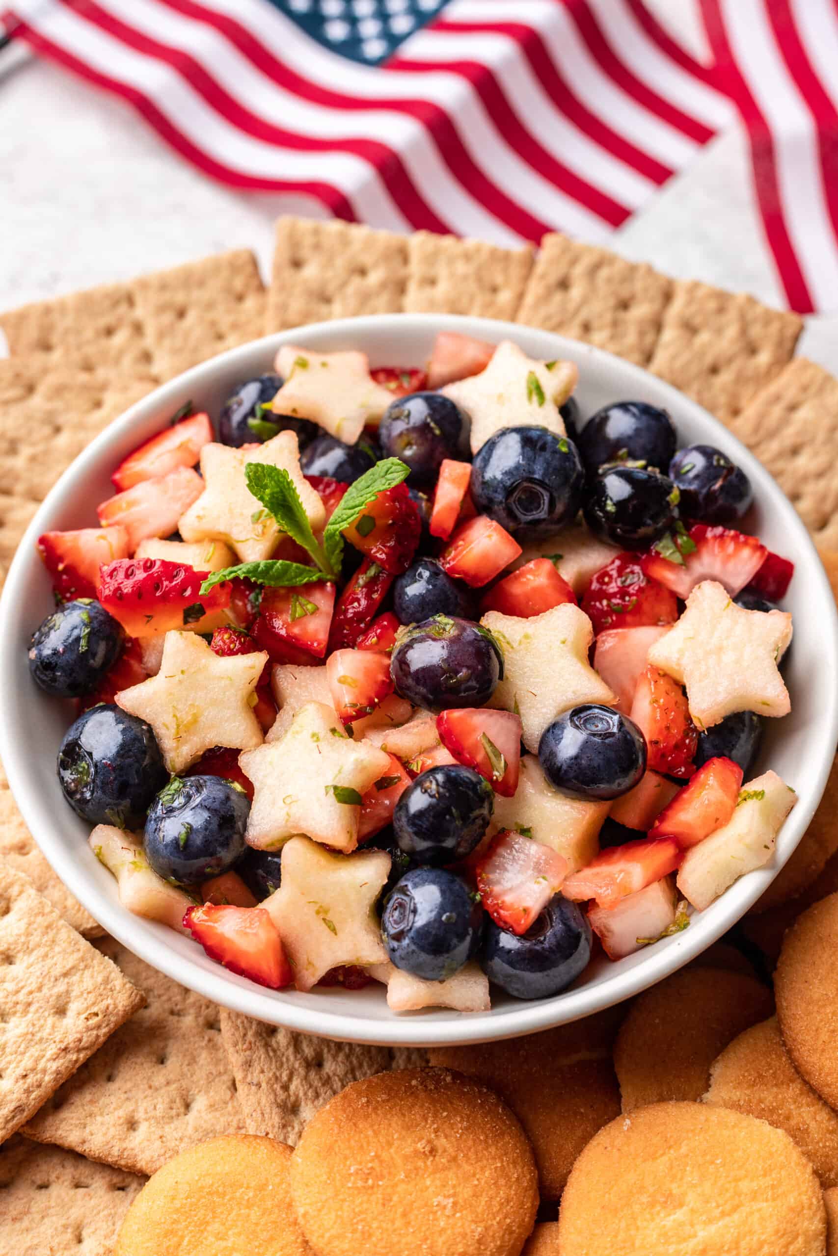 Red, white, and blue fruit salsa in a white bowl with American flags behind it.