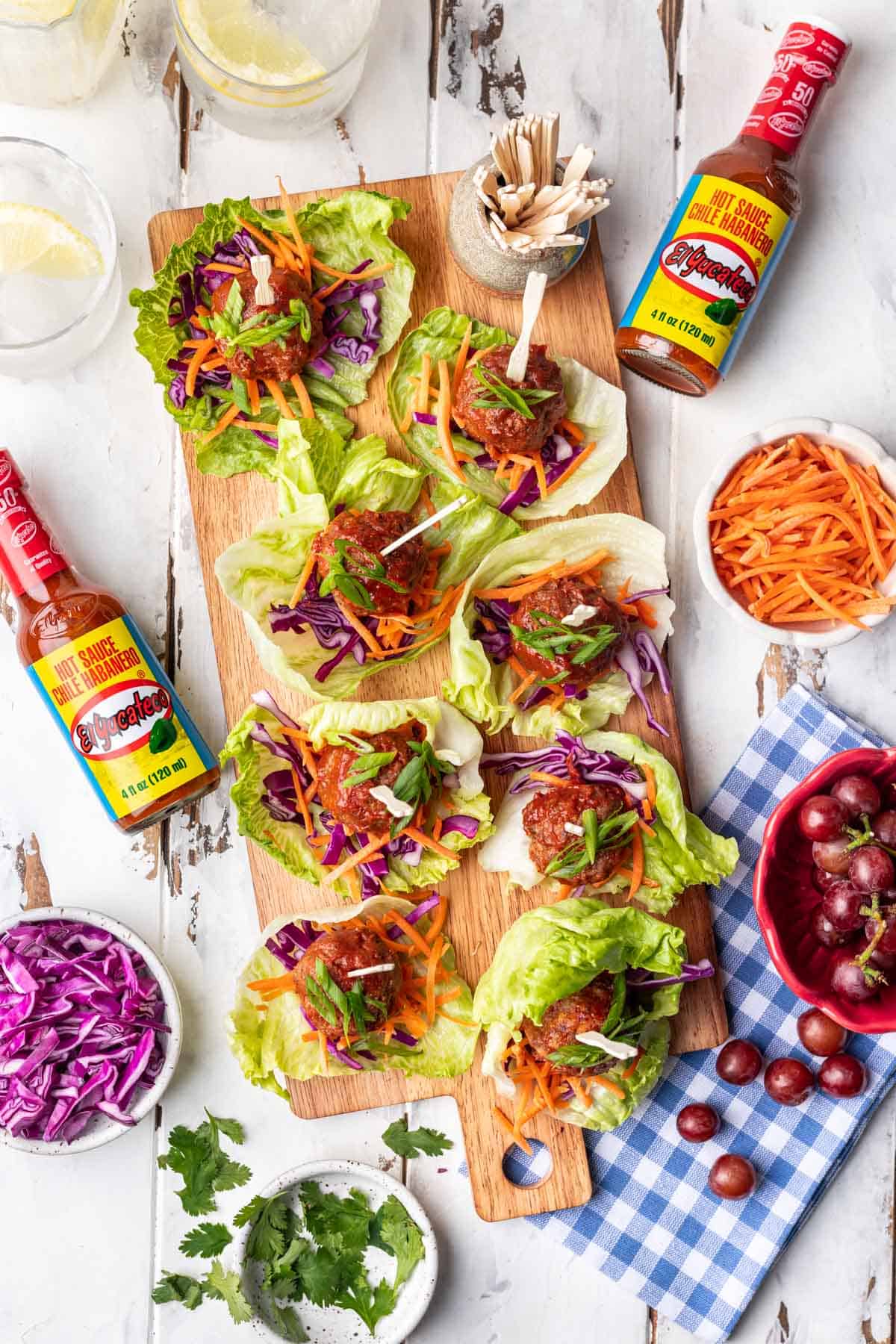 Spicy meatballs on a serving platter with lettuce cups and toppings.