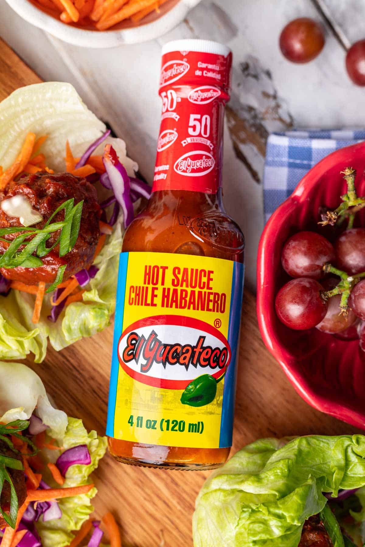 El Yucateco Chile Habanero hot sauce surrounded by spicy meatballs in lettuce cups.