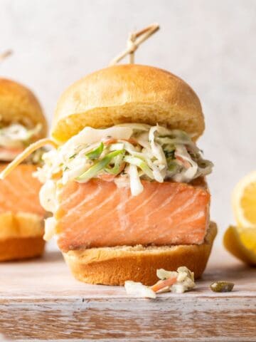 A salmon slider on a brioche bun with coleslaw.