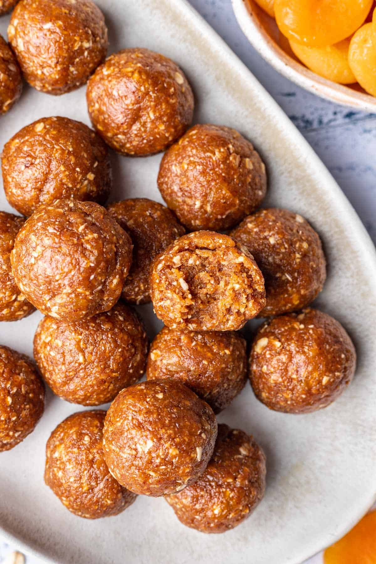 Apricot bliss balls on a serving platter, one has a bite taken out.