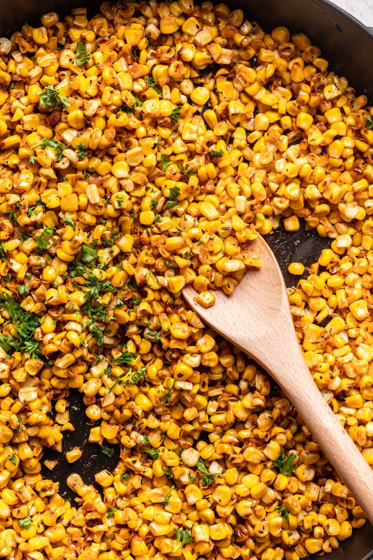 Blackened corn scooped with a wooden spoon.