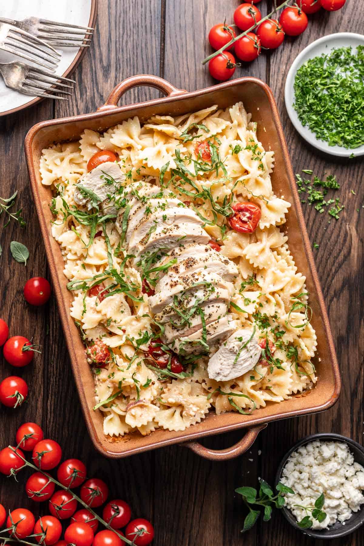 Chicken feta pasta in a baking dish with chopped basil on top.