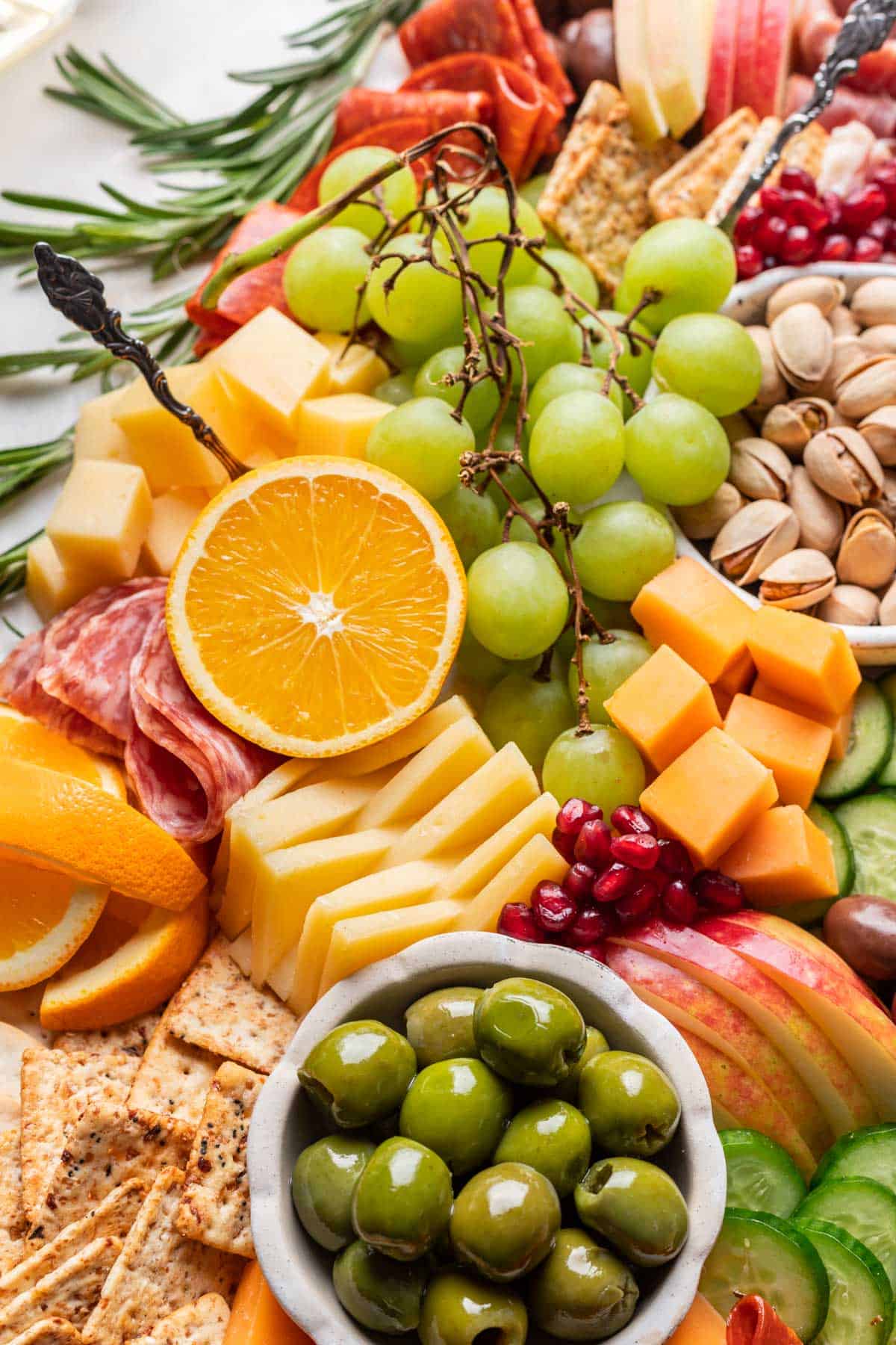 Closeup of cheeses, meats, fruits, and olives on a Christmas charcuterie board.