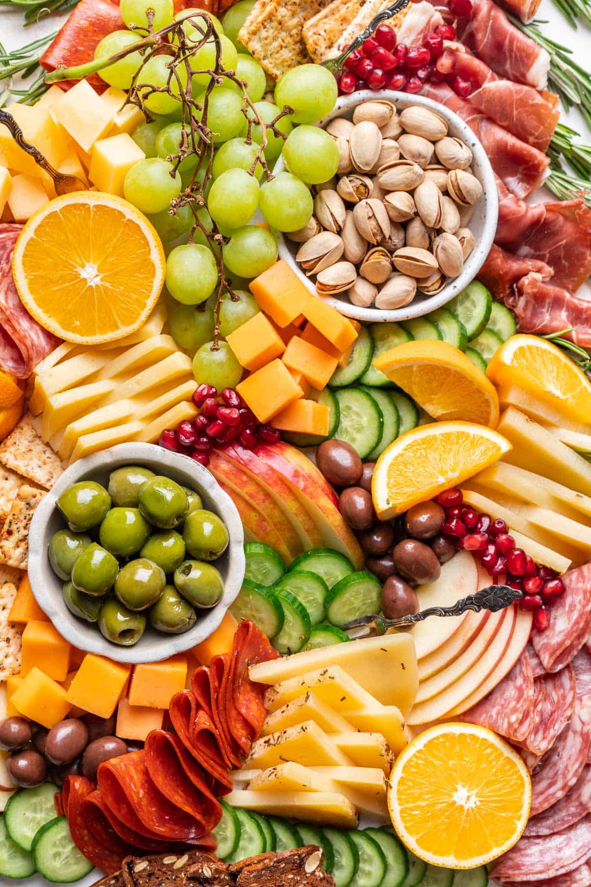 Meats, cheeses, sliced fruits, olives, nuts, and veggies make up a Christmas charcuterie board.