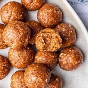 Apricot bliss balls on a serving platter with one with a bite taken out.