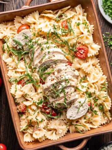 Chicken feta pasta in a baking dish with fresh basil on top.