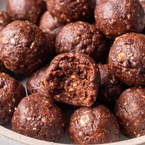 Chocolate bliss balls on a platter with one with a bite taken out.