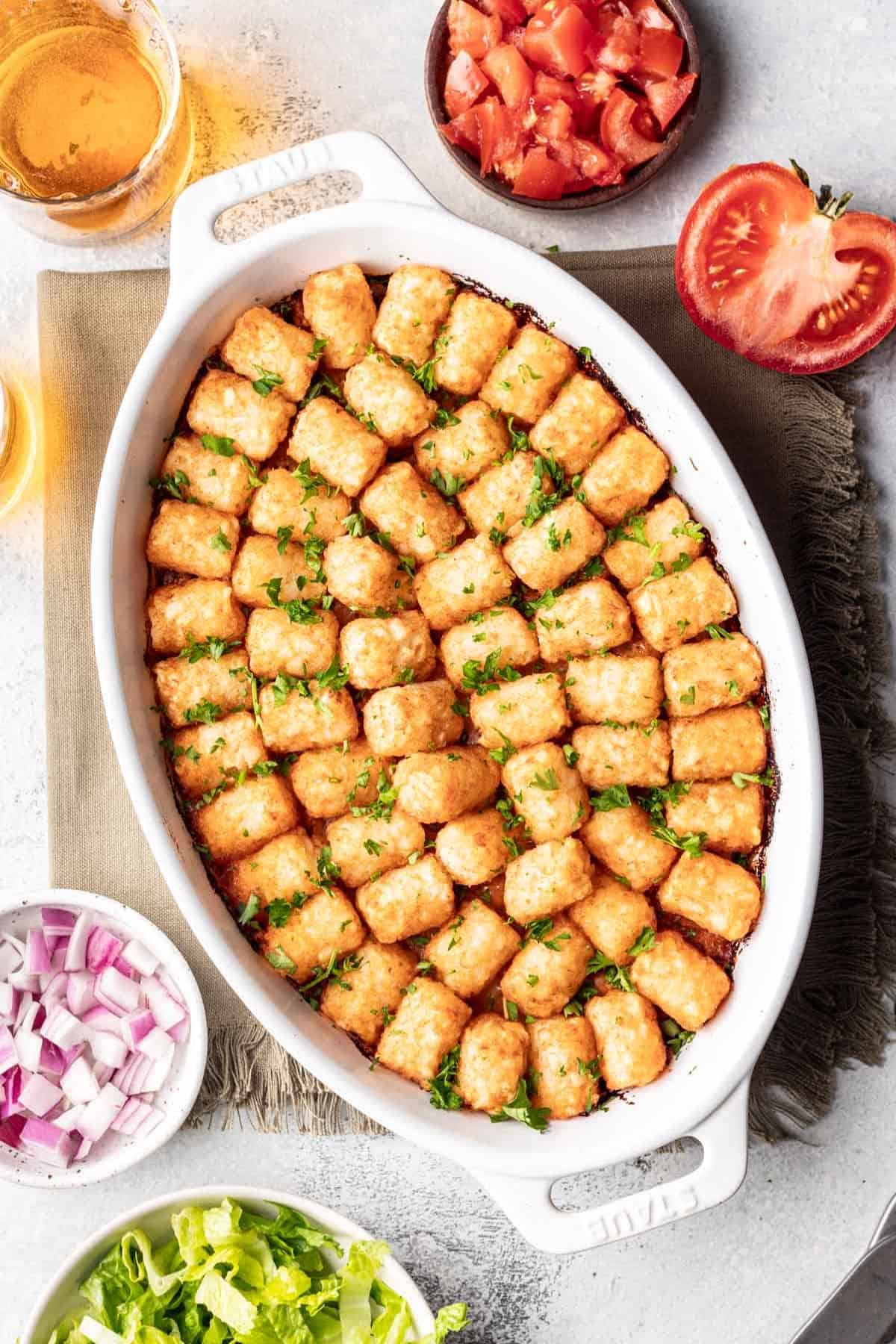Cheeseburger tater tot casserole in an oval baking dish with tater tots placed in concentric circles on top.
