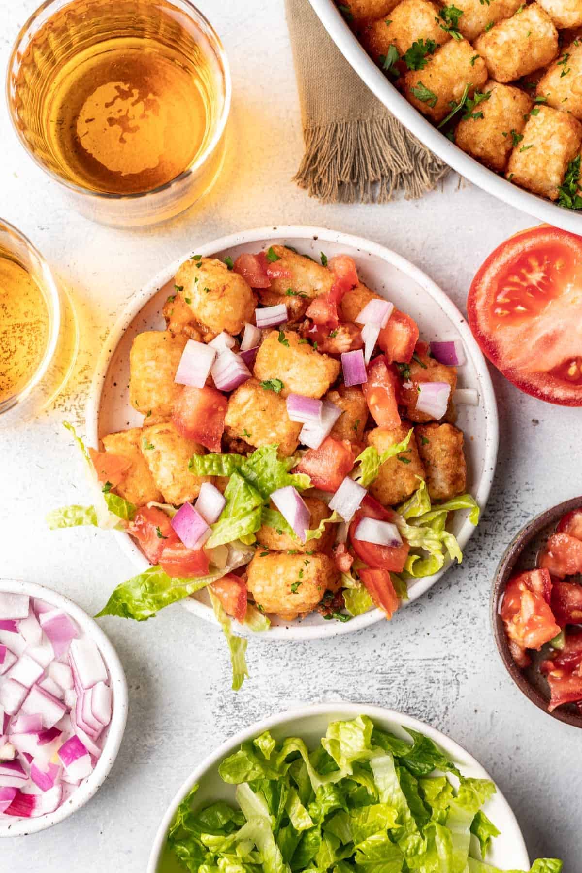 Cheeseburger tater tot casserole served with lettuce, tomato, and onion.