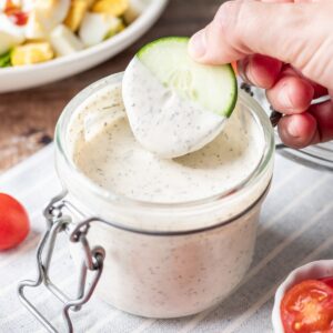 Dipping a cucumber in greek yogurt ranch dressing.