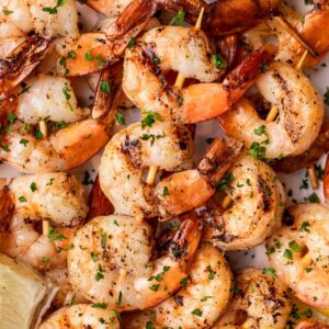 Smoked shrimp on skewers piled on a plate.