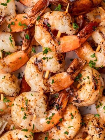 Smoked shrimp on skewers piled on a plate.