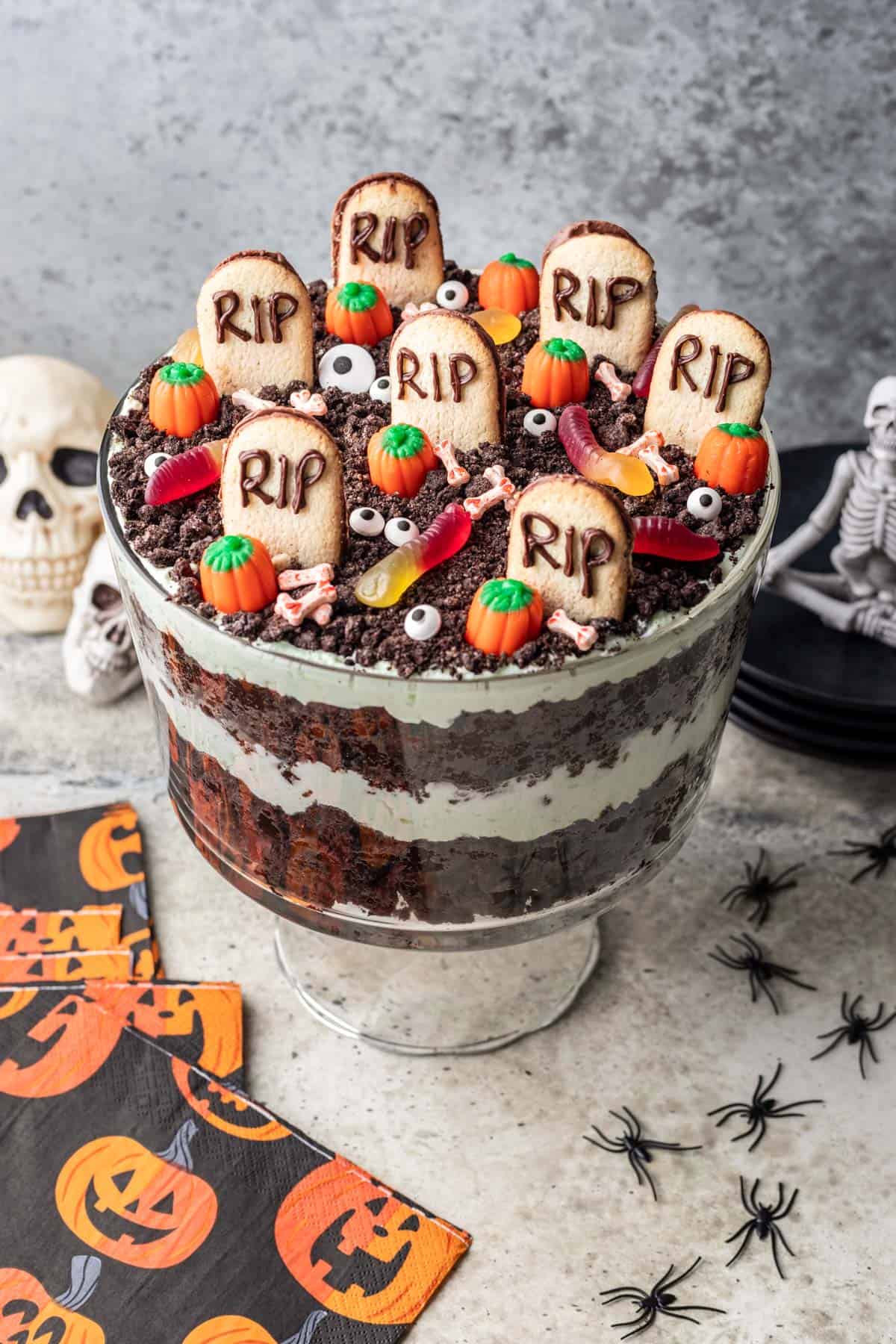 Halloween trifle in a trifle dish with spooky decorations on top.
