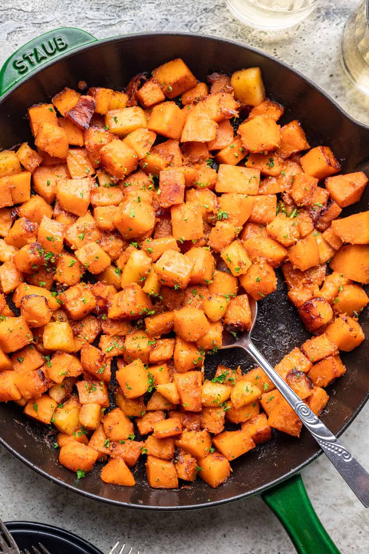 Sautéed butternut squash in a skillet with a serving spoon.
